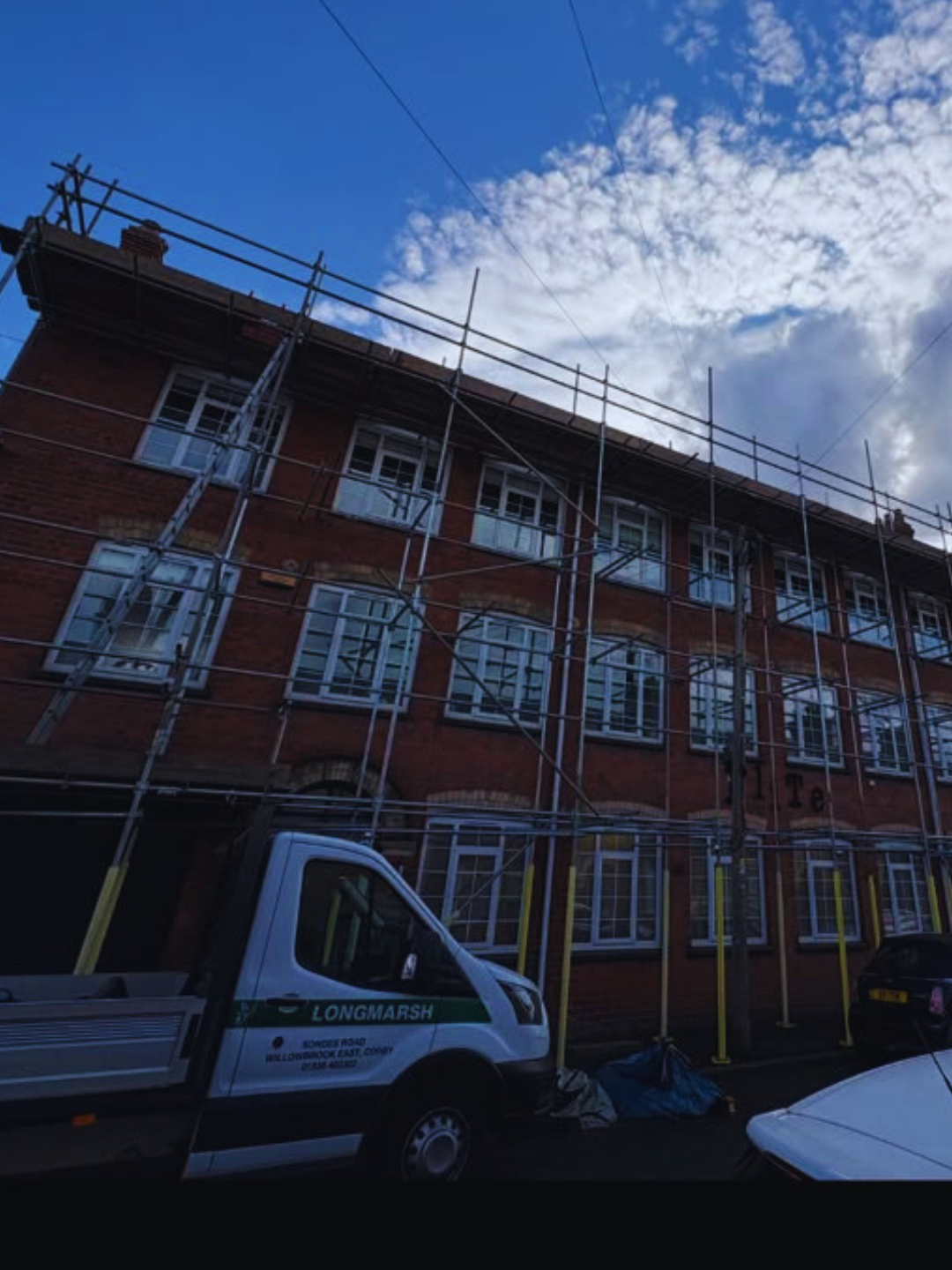 Pavement scaffolding to a three storey brick building on a town street