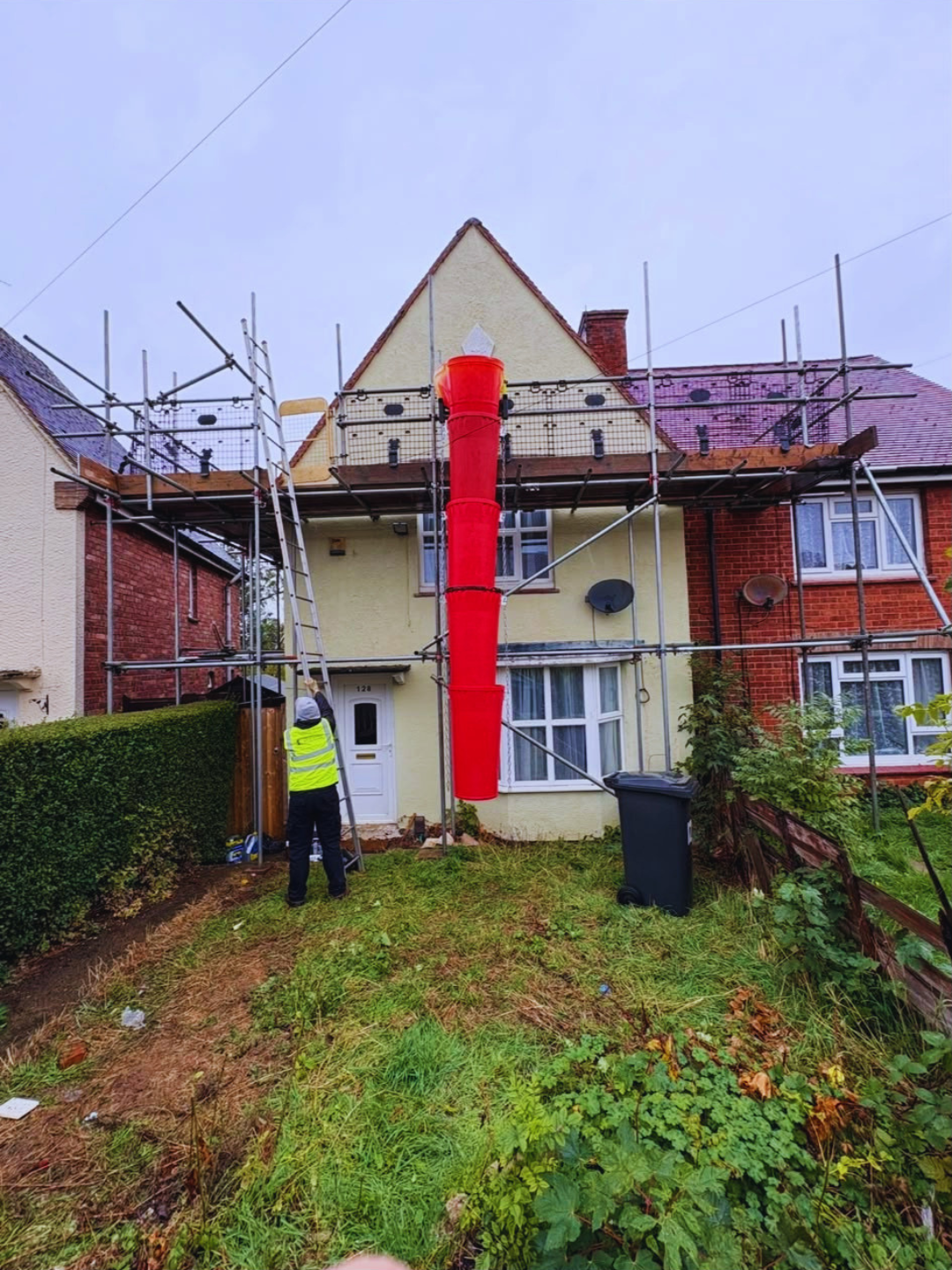 Scaffolder working at a roof scaffold with red debris chute